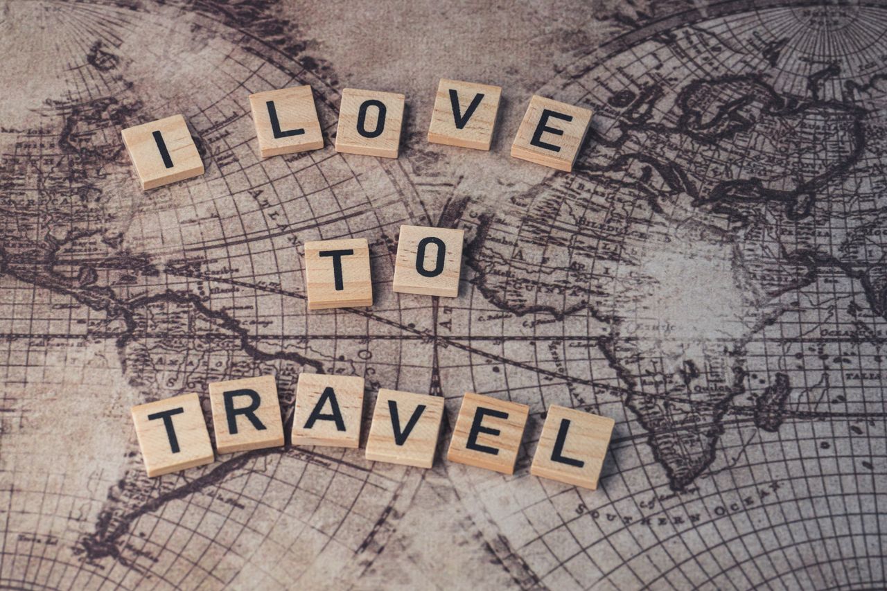 Offerings Wood scrabble tiles spelling I Love to Travel on a vintage map.